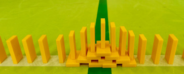 Gelbe Dominosteine bilden eine Brücke auf grünem Boden