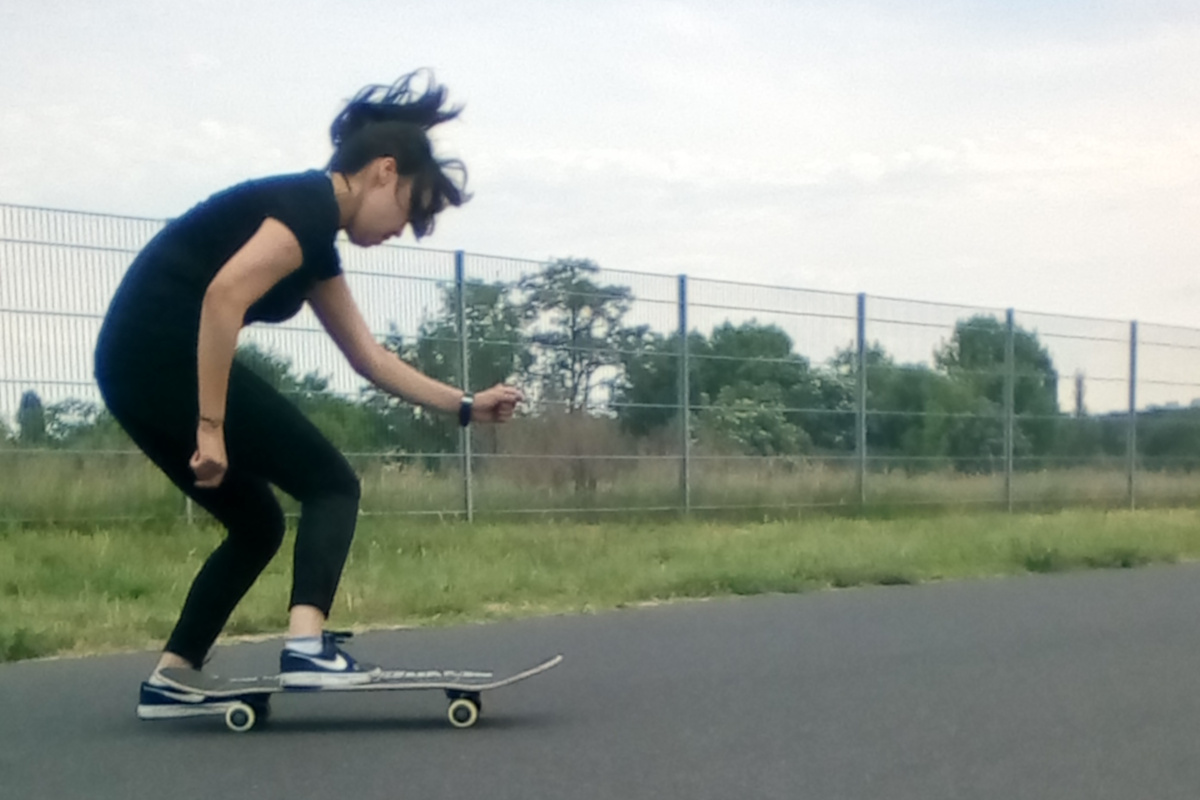 Maedchen macht einen Trick mit ihrem Skateboard